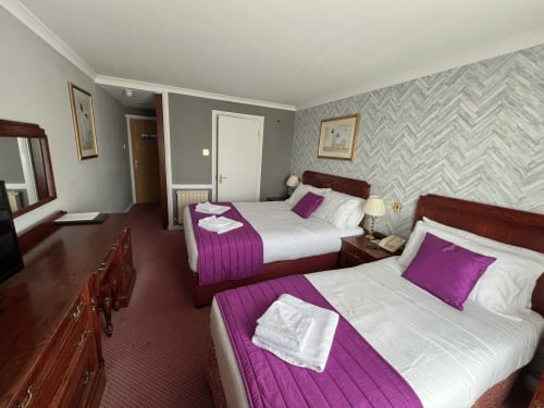 Treble Room at La Trelade Hotel in St Martins with two double beds, purple bedding, wood furnishings, and herringbone