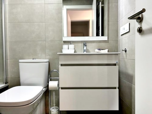 Baño moderno en apartamento Holibai, Baiona con lavamanos blanco, inodoro y paredes de azulejo