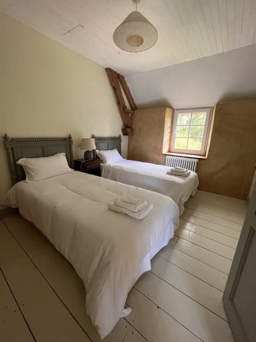 Cozy twin bedroom at Domaine du Tertre Ychot in Dol de Bretagne with white linens and sloped ceiling