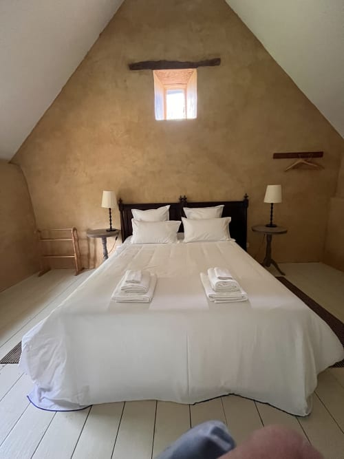 Rustic attic bedroom at Domaine du Tertre Ychot with white bedding, dark wooden bed frame, and skylights in Dol de Bretagne