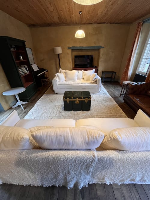 Spacious living room at Domaine du Tertre Ychot with cream sofas, fireplace, and vintage trunk decor