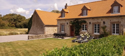 Stone cottage with golden roof, garden loungers, and patio at Domaine De La Ronville, France