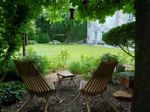 Coin détente ombragé du Logis des Tourelles avec transats face à la pelouse soignée à Cognac