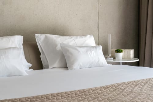 Luxuriöses Bett mit weißer Bettwäsche und Kissen im Boutique-Hotel Le Pavillon M in Grignan