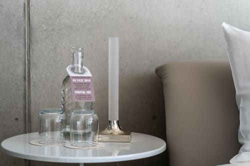 Eleganter Nachttisch im Le Pavillon M mit Wassergläsern, Willkommensflasche, Kerze und grauem gepolstertem Kopfteil in Grignan.