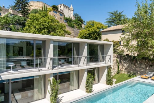 Modern white villa with pool at Le Pavillon M guesthouse in Grignan, France, featuring glass balconies and historic castle