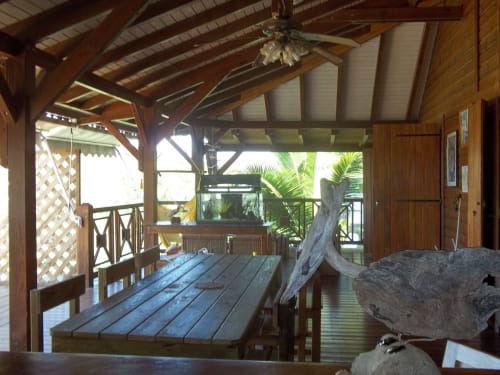Terrasse couverte avec table à manger à la villa Les Hauts De Deshaies, vue sur le jardin tropical et la mer à Deshaies