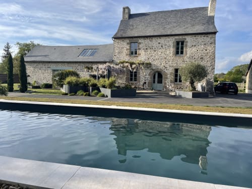 Stone manor house at Manoir de la Nogrie in Val d'Izé, France, with swimming pool and manicured gardens
