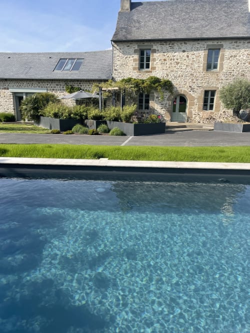 Manoir de la Nogrie's stone manor house with modern pool and manicured gardens in Val d'Izé, France