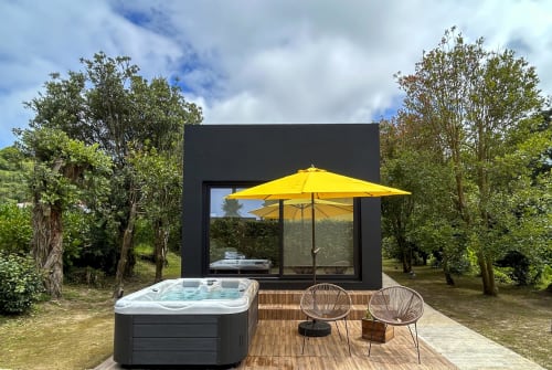 Black Cabin at Villa Várzea with hot tub, yellow umbrella, and garden seating in Várzea