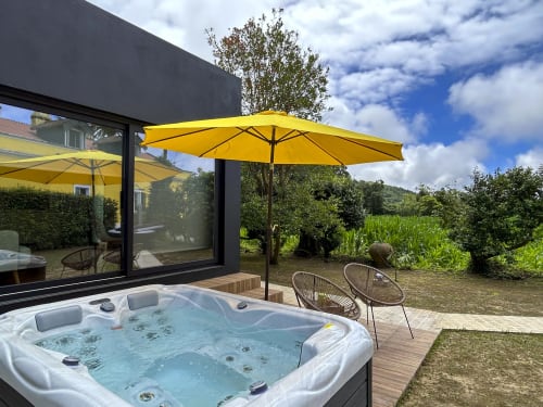 Hot tub with yellow umbrella at Villa Várzea in Várzea, Portugal, overlooking countryside gardens
