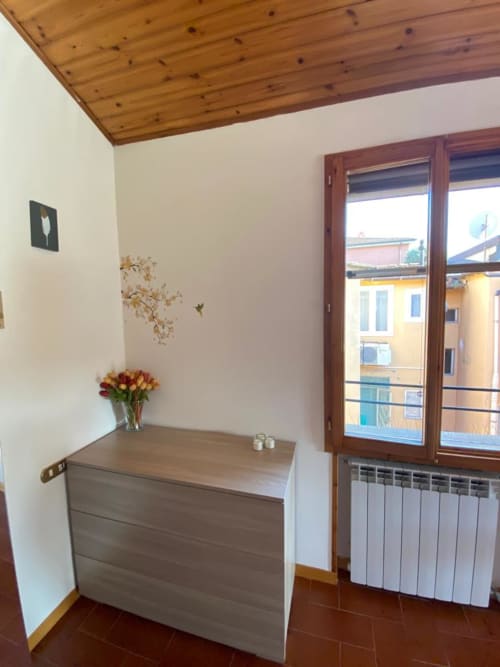 Luminosa camera all'Appartamento Giusto Bologna con soffitto in legno, comò fiorito, termosifone e porte scorrevoli