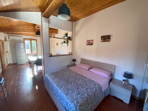 Camera da letto moderna in L'Appartamento Giusto Bologna con letto queen, soffitto in legno, lampada a sospensione e living open space con