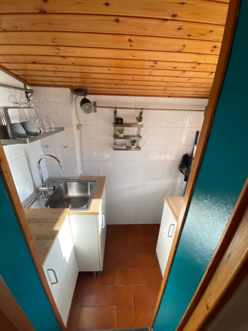 Cucina compatta in L'Appartamento Giusto Bologna con lavello, mobili bianchi, soffitto in legno e parete con piastrelle bianche
