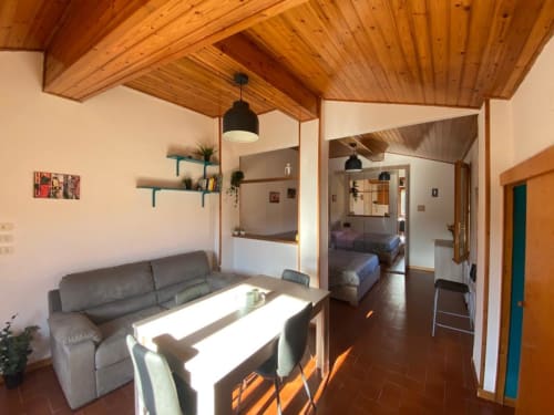 L'appartamento Social Costa presso L'Appartamento Giusto a Bologna presenta soffitto in legno, divano grigio, tavolo da pranzo e zona living aperta