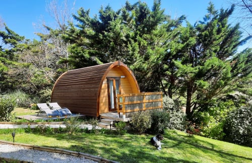 Wooden barrel glamping pod at Belloréade with deck, garden views, and loungers surrounded by trees in Belloc