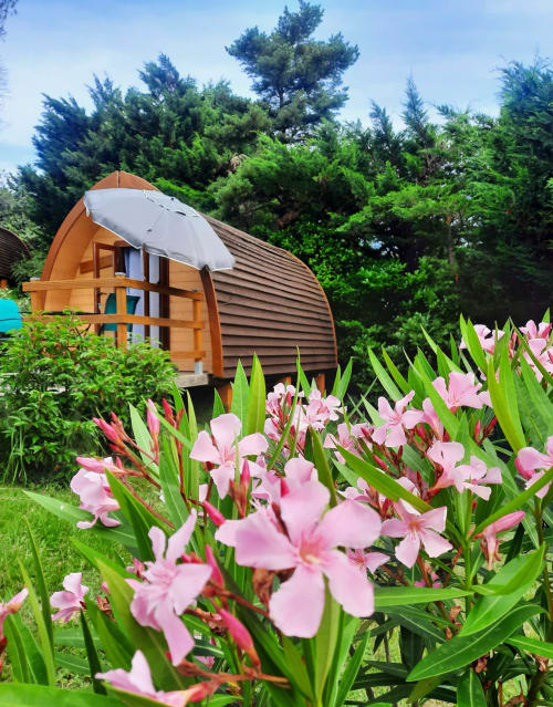 Orange glamping refuge with private balcony surrounded by pink flowers and lush gardens at Belloréade, Belloc
