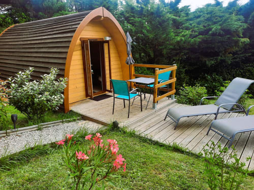 Yellow glamping pod with turquoise chairs on wooden deck, surrounded by garden and lounge chairs at Belloréade, Belloc