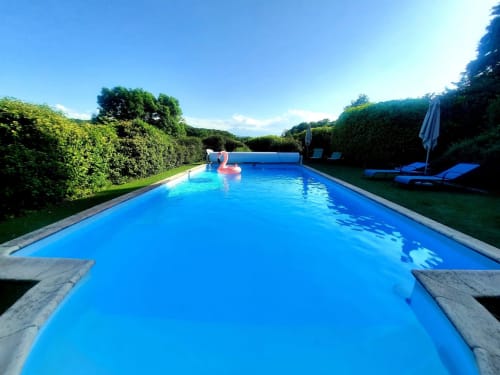 Luxurious rectangular swimming pool at Belloréade B&B in Belloc, France, surrounded by lush green hedges and lounge chairs
