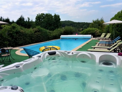 Hot tub with turquoise water overlooking swimming pool and garden at Belloréade bed and breakfast in Belloc