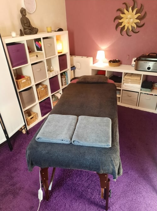 Massage room at Belloréade B&B in Belloc with treatment bed, purple carpet, storage units, and decorative sun wall art