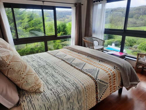 Spacious bedroom at Belloréade B&B with mountain views through large windows, patterned bedding, and desk workspace