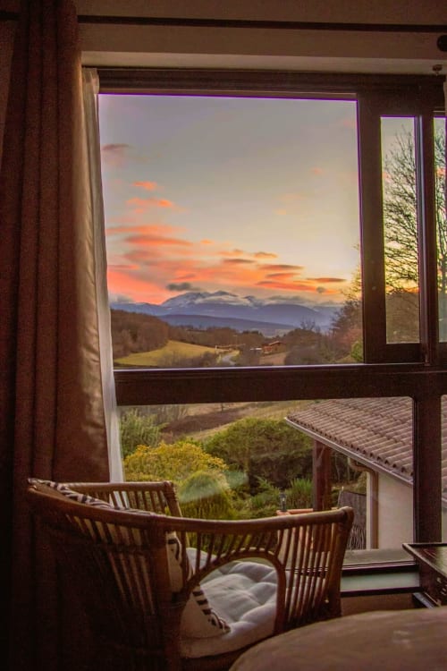 Mountain sunset view from Room Safari at Belloréade B&B in Belloc, with wicker chairs on terrace overlooking volcanic peaks
