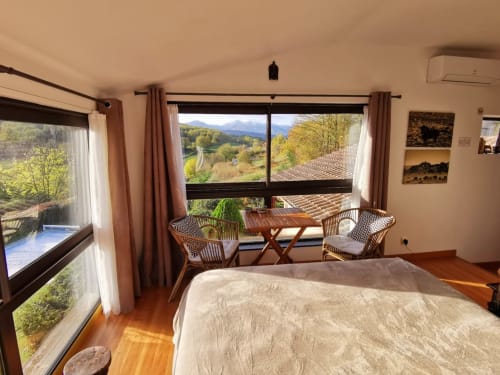 Room Safari at Belloréade B&B with mountain views, wooden bed, wicker chairs, and scenic window overlooking Belloc valley