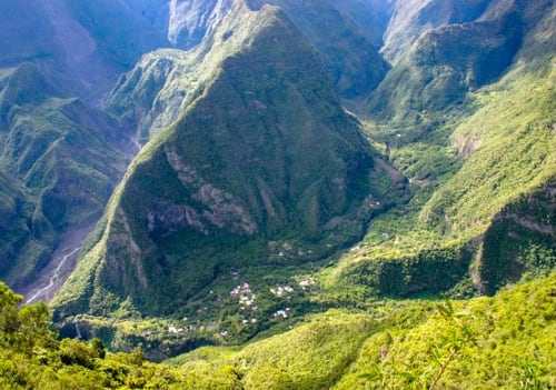 Vallée montagnarde luxuriante avec bâtiments dispersés nichés sur les pentes verdoyantes près de La Plaine des Cafres, Réunion