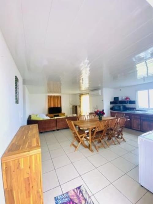 Espace de vie ouvert à la villa Case Vi D'O à La Plaine des Cafres avec table à manger, mobilier en bois et vue sur les montagnes