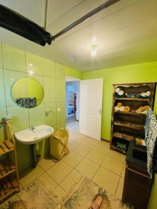 Salle de bains vert anis éclatant à la villa Case Vi D'O avec lavabo sur colonne, miroir rond et meuble de rangement foncé à La Plaine des