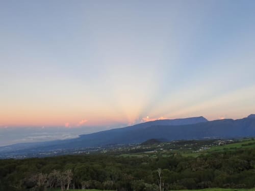 Vue sur les montagnes depuis la villa Case Vi D'O au coucher de soleil, La Plaine des Cafres, Réunion, avec pentes boisées et vallée en contrebas
