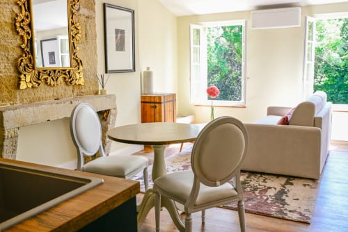 Elegant studio at Pavillon Des Millésimes with cream furnishings, fireplace, round table, and garden views through large