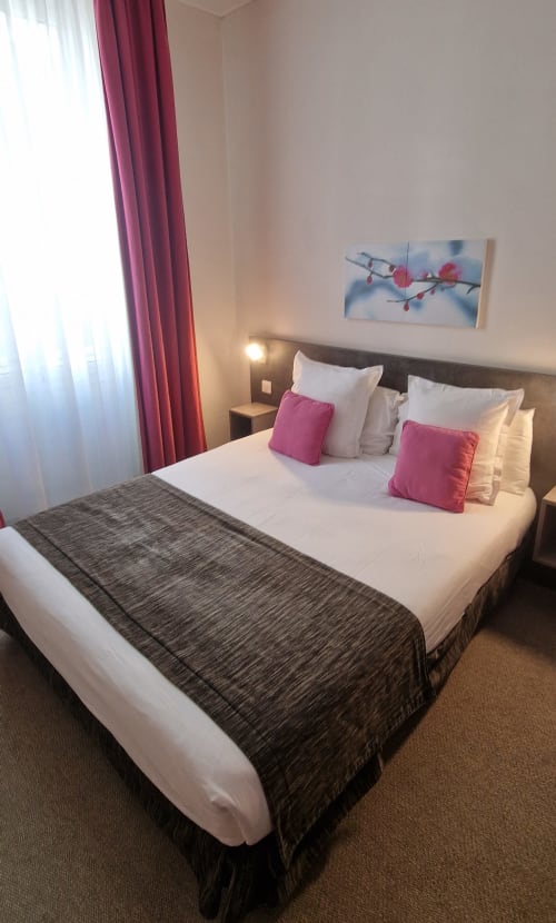 Camera d'albergo moderna presso l'Hôtel De La Fontaine a Nizza con letto queen, accenti rosa e vista sulla città