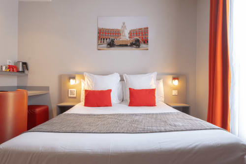 Modernes Hotelzimmer mit roten Akzenten, weißer Bettwäsche und Stadtbildkunst im Hôtel De La Fontaine in Nizza