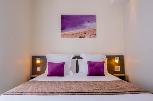Camera Doppia Superior presso l'Hôtel De La Fontaine a Nizza con cuscini accent viola, opere d'arte marina e lampade da comodino