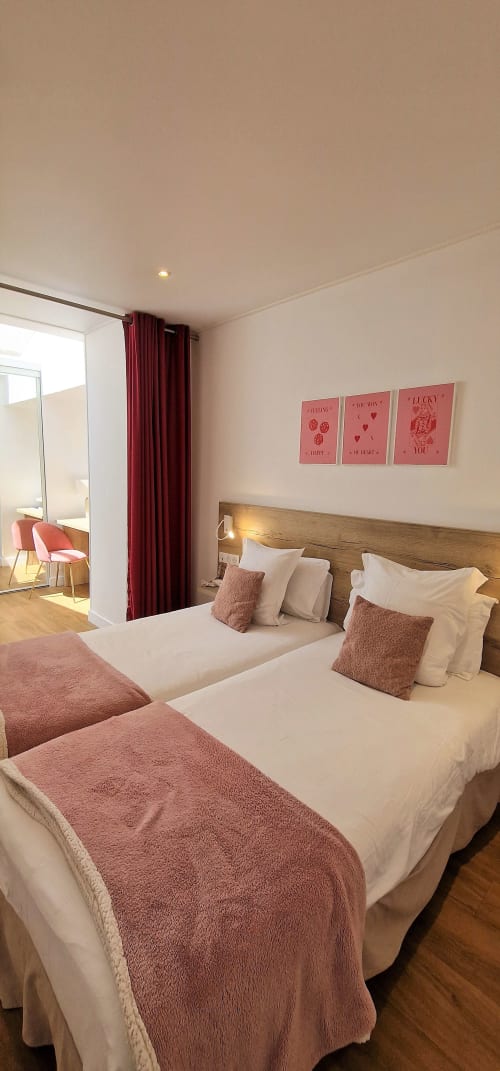 Camera d'hotel moderna all'Hôtel De La Fontaine a Nizza con due letti, testata in legno, tende bordeaux e arte murale rosa