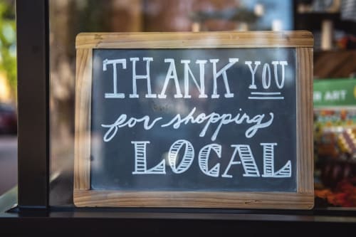 Chalkboard sign at Au Gite d'Isigny B&B in Isigny-sur-Mer thanking customers for shopping local