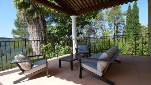 Lounge im Freien auf überdachter, schattiger Terrasse mit Blick auf den Pool, die Gärten und den Berg Estérel
