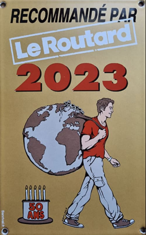 Couverture du guide de voyage Le Routard 2023 : un homme portant le globe terrestre, célébrant 50 ans