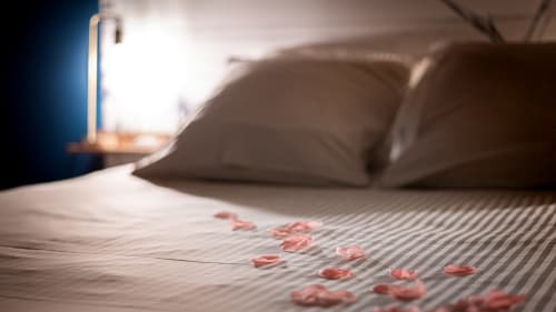 Chambre romantique à la Villa Eden Bleu avec pétales de rose sur le lit, oreillers et lampe de chevet à Biscarrosse