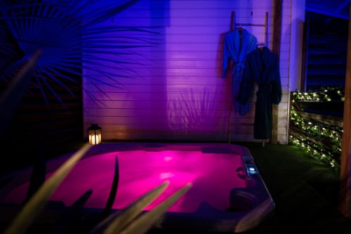 Jacuzzi rose fluo illuminé à la Villa Eden Bleu de Biscarrosse, ambiance violette et plantes tropicales