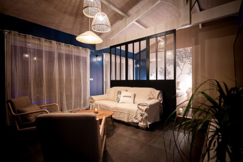 Chambre moderne à Villa Eden Bleu Biscarrosse : canapé crème, luminaires suspendus, mur bleu accent et cloison vitrée.