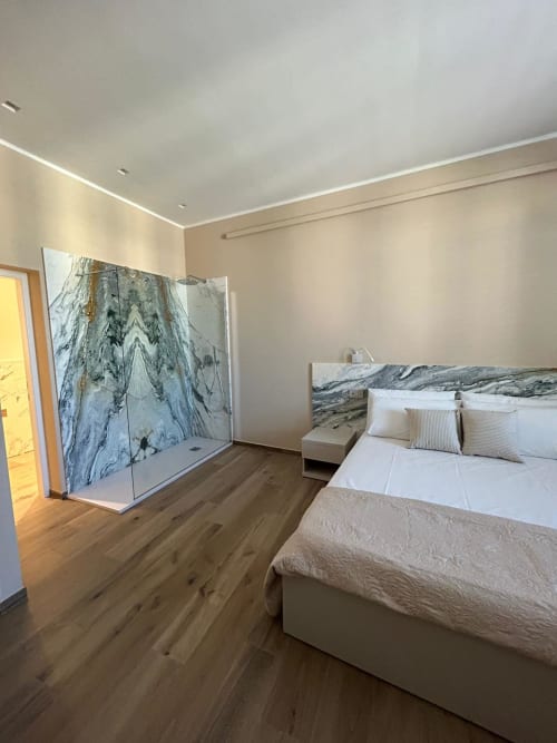 Camera moderna a Breccia nel Mare con doccia in marmo, letto queen, pavimento in legno e testata con motivi marmorizzati