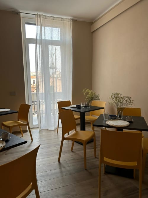 Moderna sala da pranzo del Breccia nel Mare B&B a Marina di Carrara con sedie giallo senape, tavoli neri e balcone con vista mare