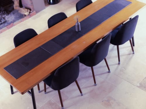 Modern wooden dining table with black chairs and dark placemats at La Guirtelle B&B in Lainsecq, France