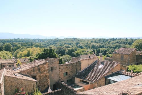 Bâtiments médiévaux en pierre surplombant une vallée verdoyante et les montagnes de Grignan, en France