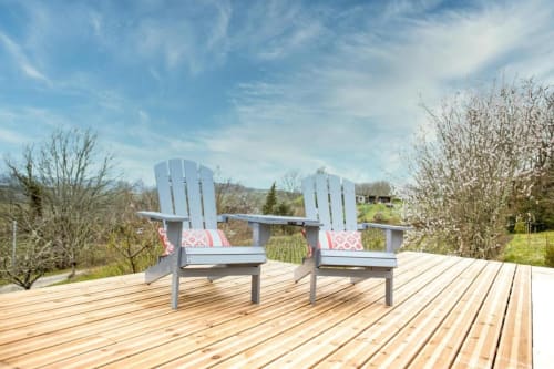 Deux chaises Adirondack bleues sur la terrasse du Château Haut Clarise à Belvès-de-Castillon, avec vue sur la campagne