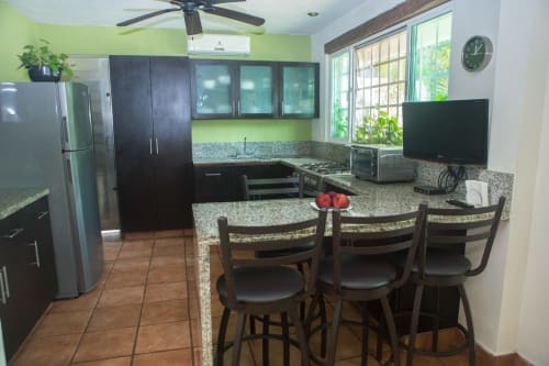 Cocina moderna con gabinetes negros, encimeras de granito, barra y electrodomésticos en villa Cozy House Downtown Cancún