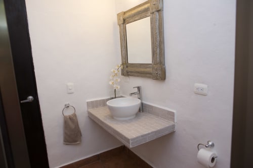 Moderno tocador de baño con lavamanos redondo blanco, espejo y encimera de azulejos en villa Cozy House Centro Cancún